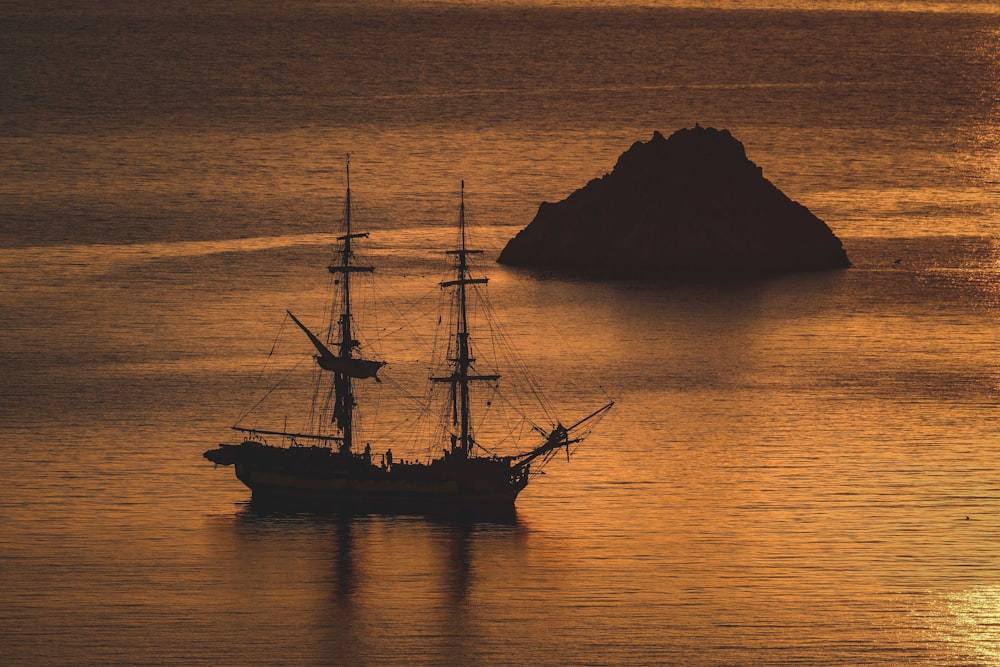 a ship sailing in the ocean at sunset