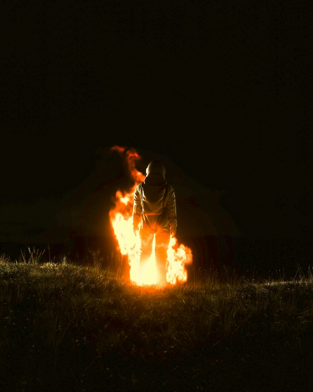 a man standing in front of a fire in the dark