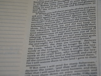 A close-up view of a page from a Bible, featuring printed text which speaks about divine retribution and behaviors of ancestors. The paper is slightly yellowed, and there are visible horizontal lines in the margins.