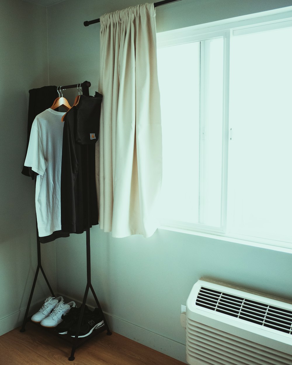 a room with a heater, clothes and a window