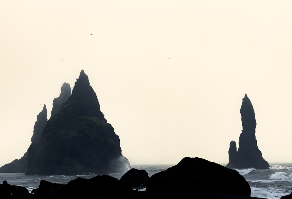 a group of rocks sitting on top of a beach next to the ocean