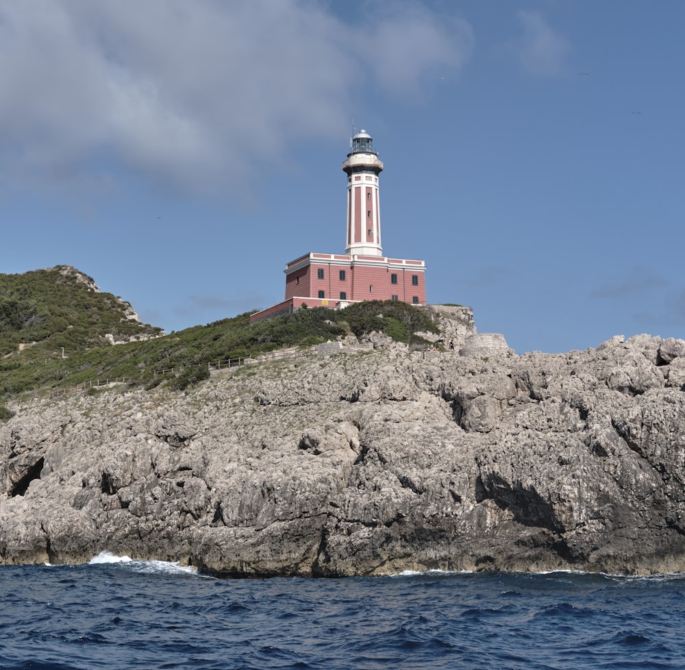 a red and white lighthouse on top of a rock formation
