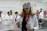 A woman wearing a virtual reality headset and holding controllers stands in a laboratory setting. She is dressed in a white lab coat and is surrounded by several people who are also in lab attire. Anatomical models are visible in the background, suggesting a medical or educational environment.