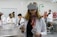 A woman wearing a virtual reality headset and holding controllers stands in a laboratory setting. She is dressed in a white lab coat and is surrounded by several people who are also in lab attire. Anatomical models are visible in the background, suggesting a medical or educational environment.