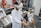 Several individuals in white lab coats are wearing virtual reality headsets in a laboratory setting. Anatomical models and educational tools are visible on tables and shelves, indicating a medical or educational environment. The individuals appear to be using hand controllers while engaged in a virtual reality experience.