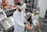 Several individuals in white lab coats are wearing virtual reality headsets in a laboratory setting. Anatomical models and educational tools are visible on tables and shelves, indicating a medical or educational environment. The individuals appear to be using hand controllers while engaged in a virtual reality experience.