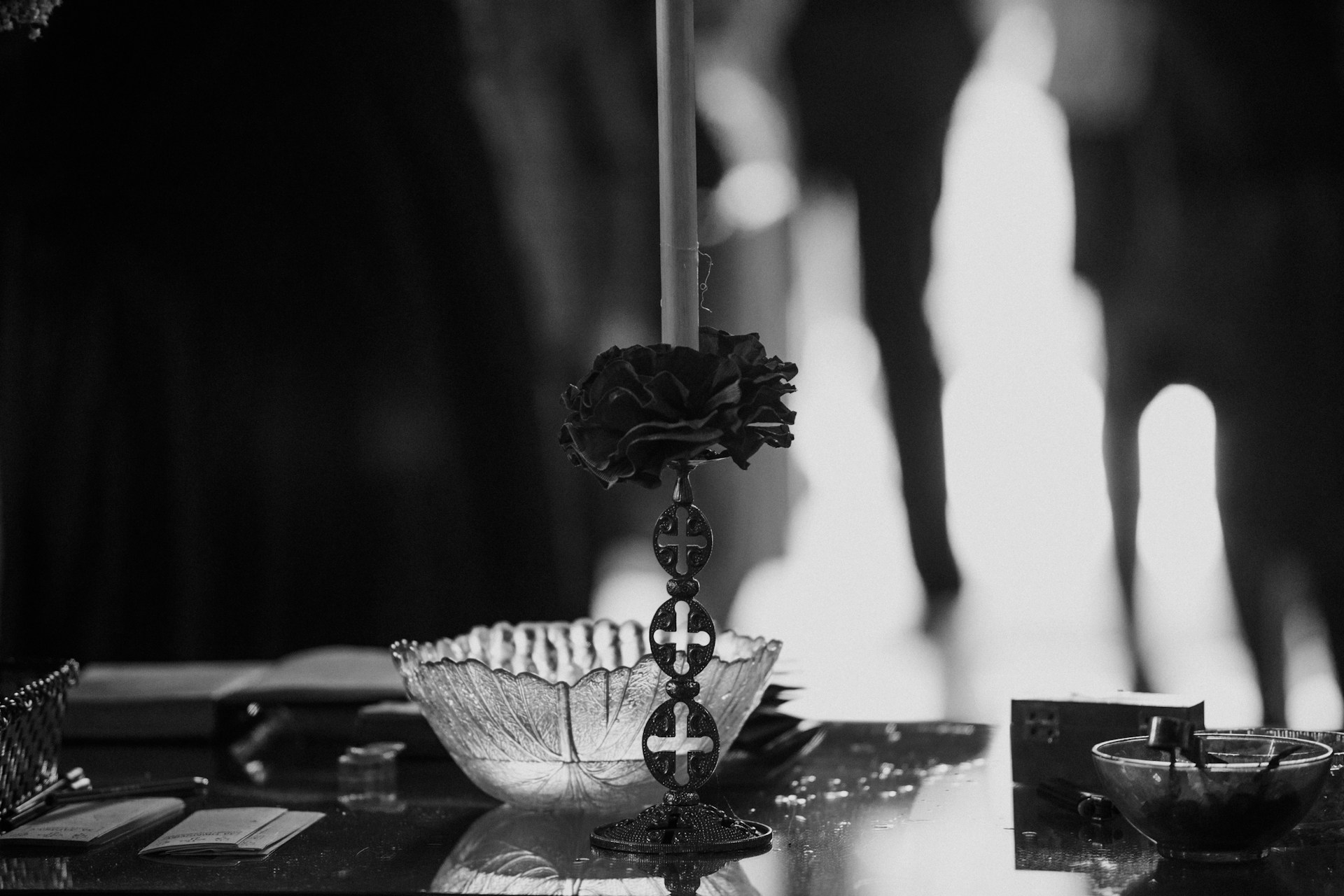 A striking black and white photograph capturing a sleek wedding setup with minimalist floral arrangements and elegant table settings under soft ambient lighting.