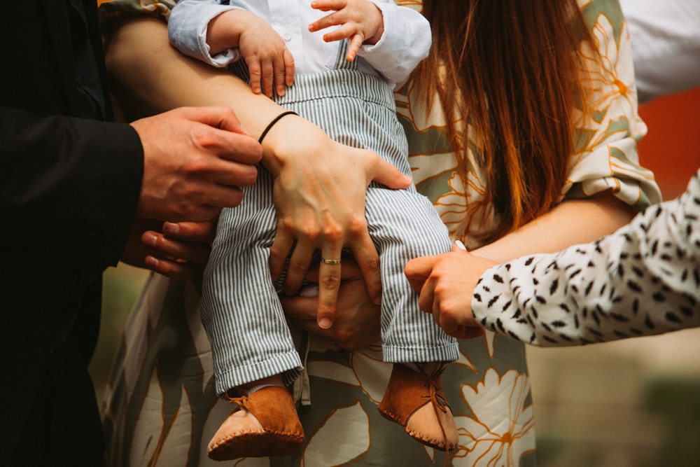 Un grupo de personas sosteniendo un bebé en sus manos