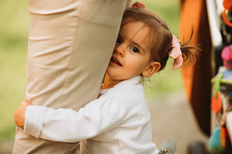 a little girl holding onto a person's leg