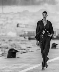 a woman walking down a sidewalk next to a body of water