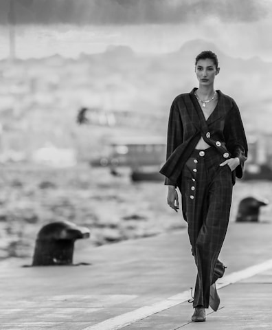 a woman walking down a sidewalk next to a body of water
