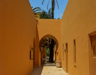 a walkway between two buildings with palm trees in the background