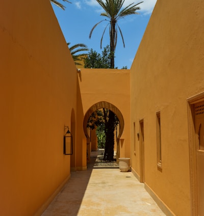 a walkway between two buildings with palm trees in the background