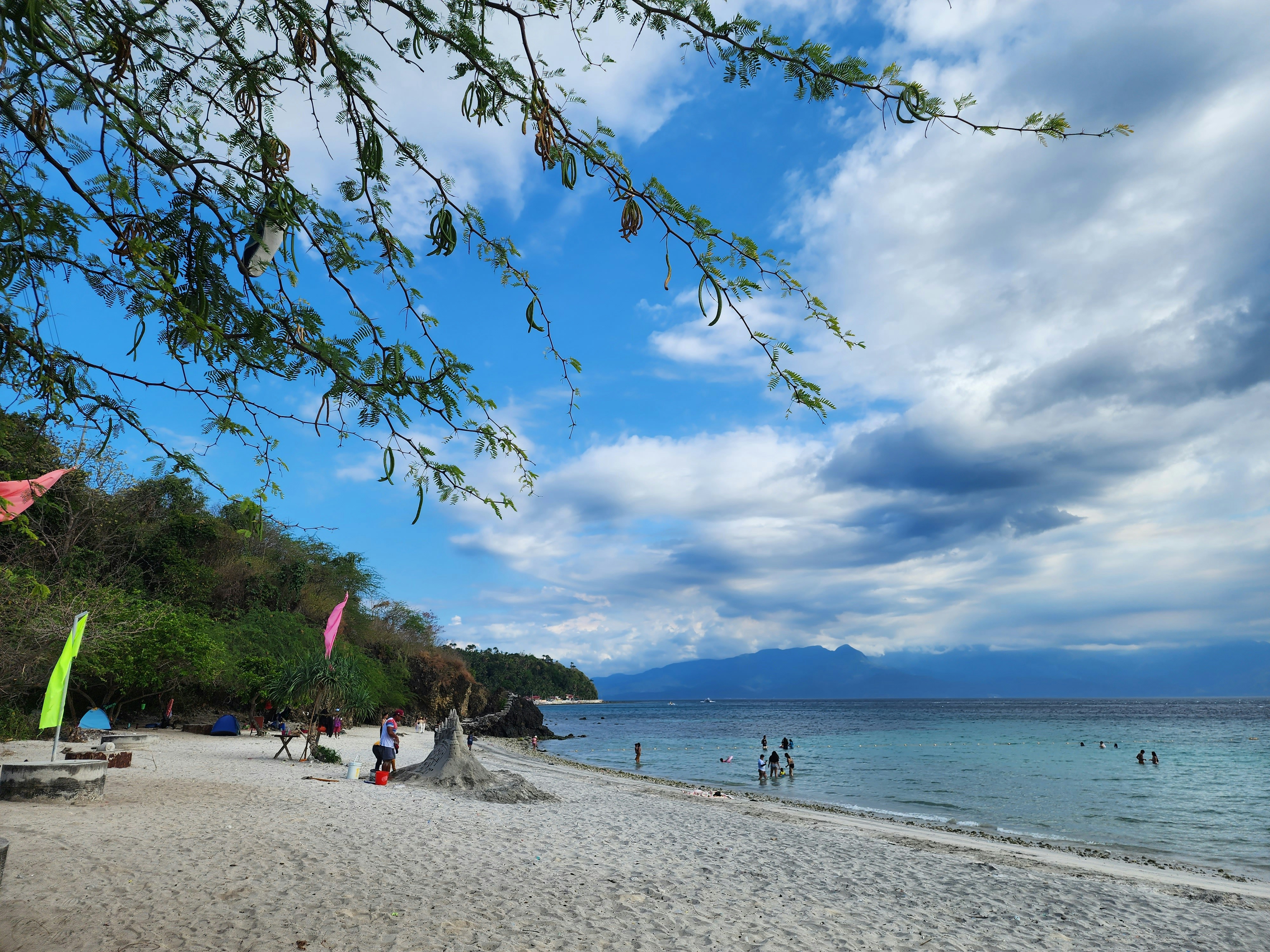 a sandy beach with people on it under a cloudy sky