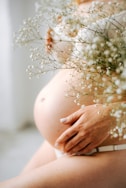 a pregnant woman holding a bouquet of baby's breath