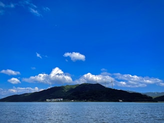 A serene landscape featuring water, wind, and sun elements.