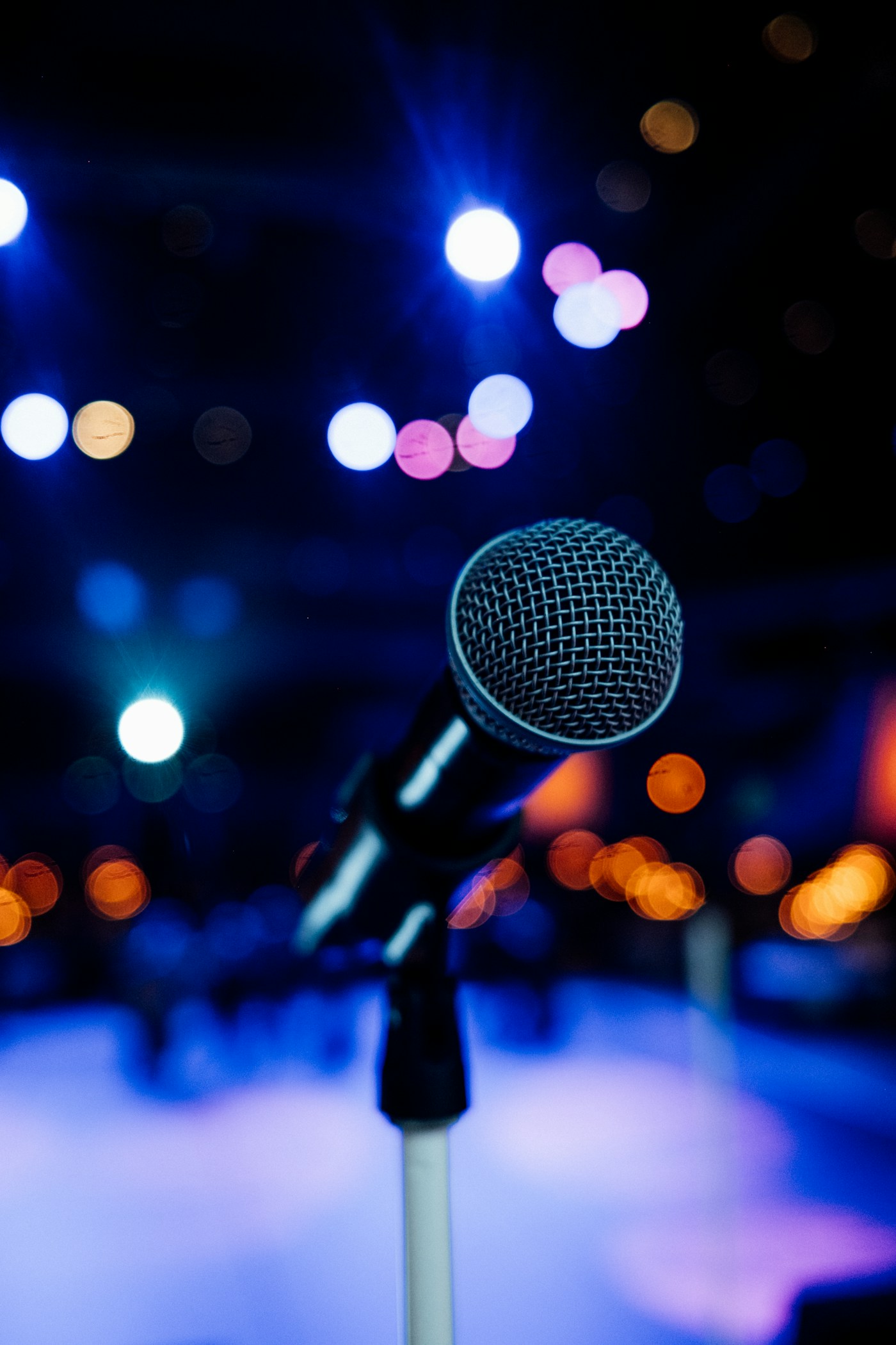 A microphone in front of stage lights; illustrative photography, not a past Chisom speaking engagement.