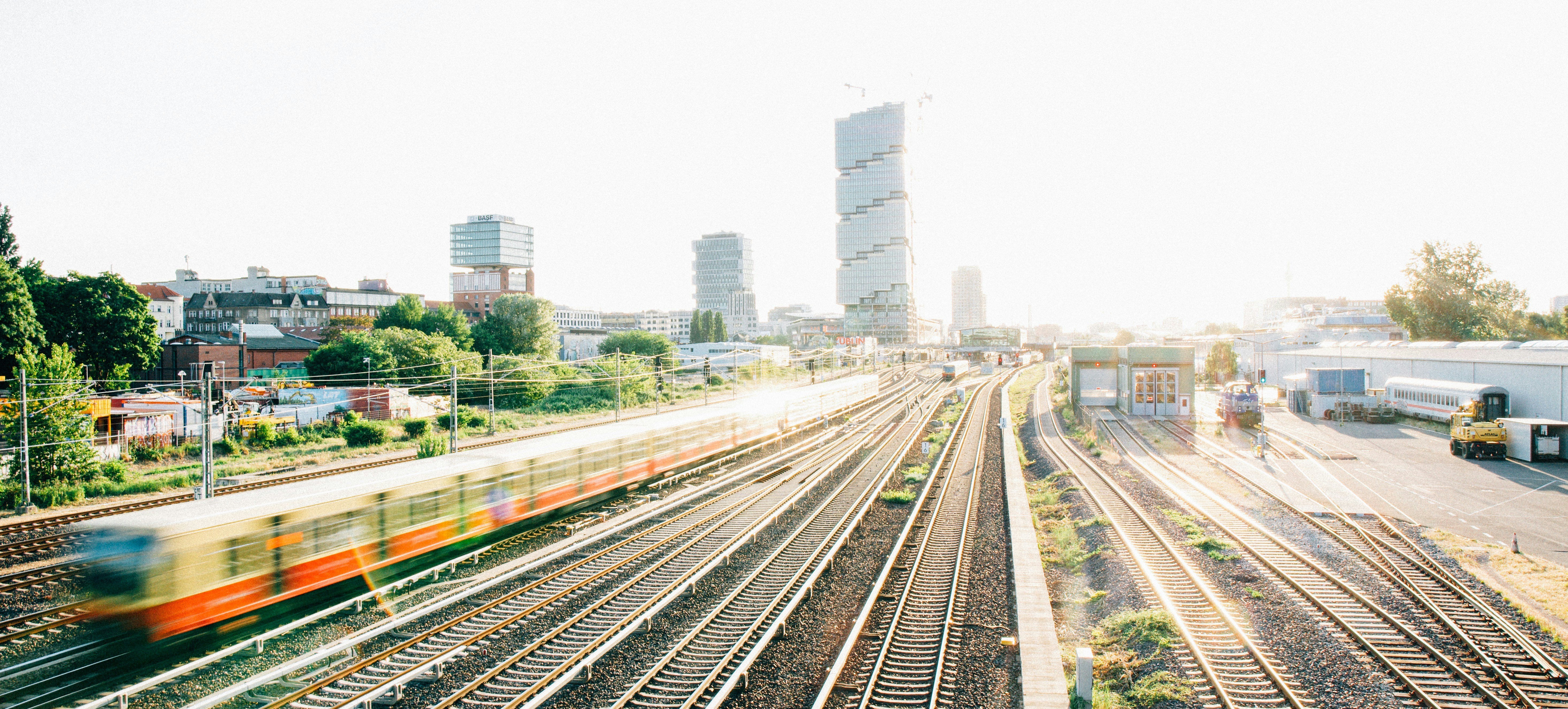 Ein Zug, der neben hohen Gebäuden auf Bahngleisen fährt