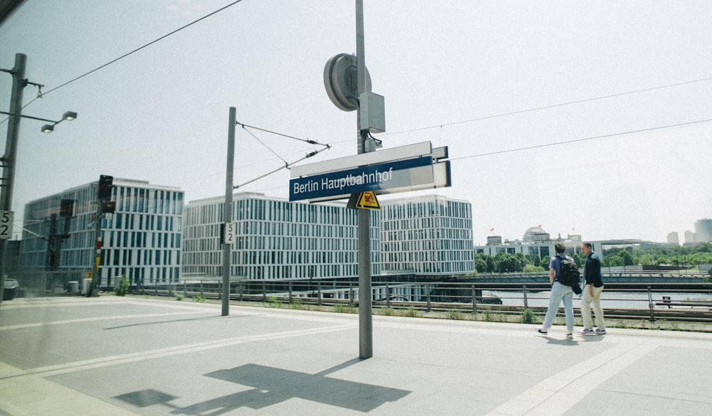 a couple of people standing next to a street sign