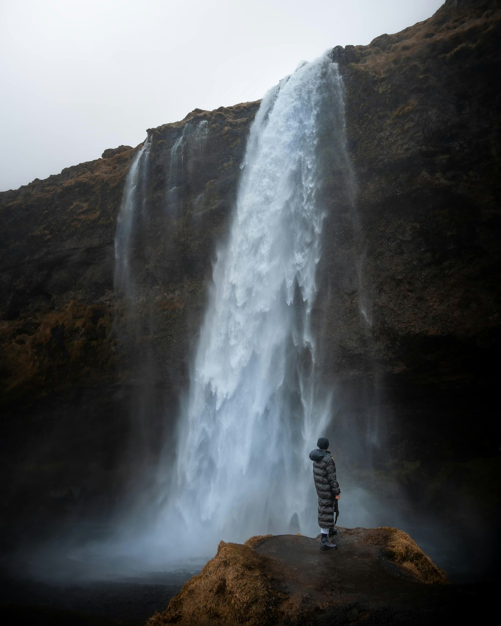 uma pessoa em pé em frente a uma cachoeira