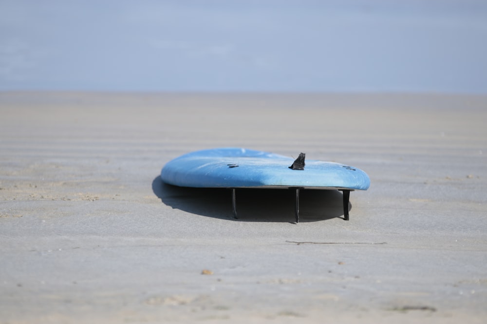 a blue surfboard sitting on top of a sandy beach