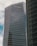 A modern high-rise building with reflective glass windows and the KPMG logo near the top. The structure features sleek, vertical lines and a mix of metal and glass materials. Another building with a curved façade is partially visible on the right side.