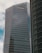 A modern high-rise building with reflective glass windows and the KPMG logo near the top. The structure features sleek, vertical lines and a mix of metal and glass materials. Another building with a curved façade is partially visible on the right side.