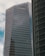 A modern high-rise building with reflective glass windows and the KPMG logo near the top. The structure features sleek, vertical lines and a mix of metal and glass materials. Another building with a curved façade is partially visible on the right side.