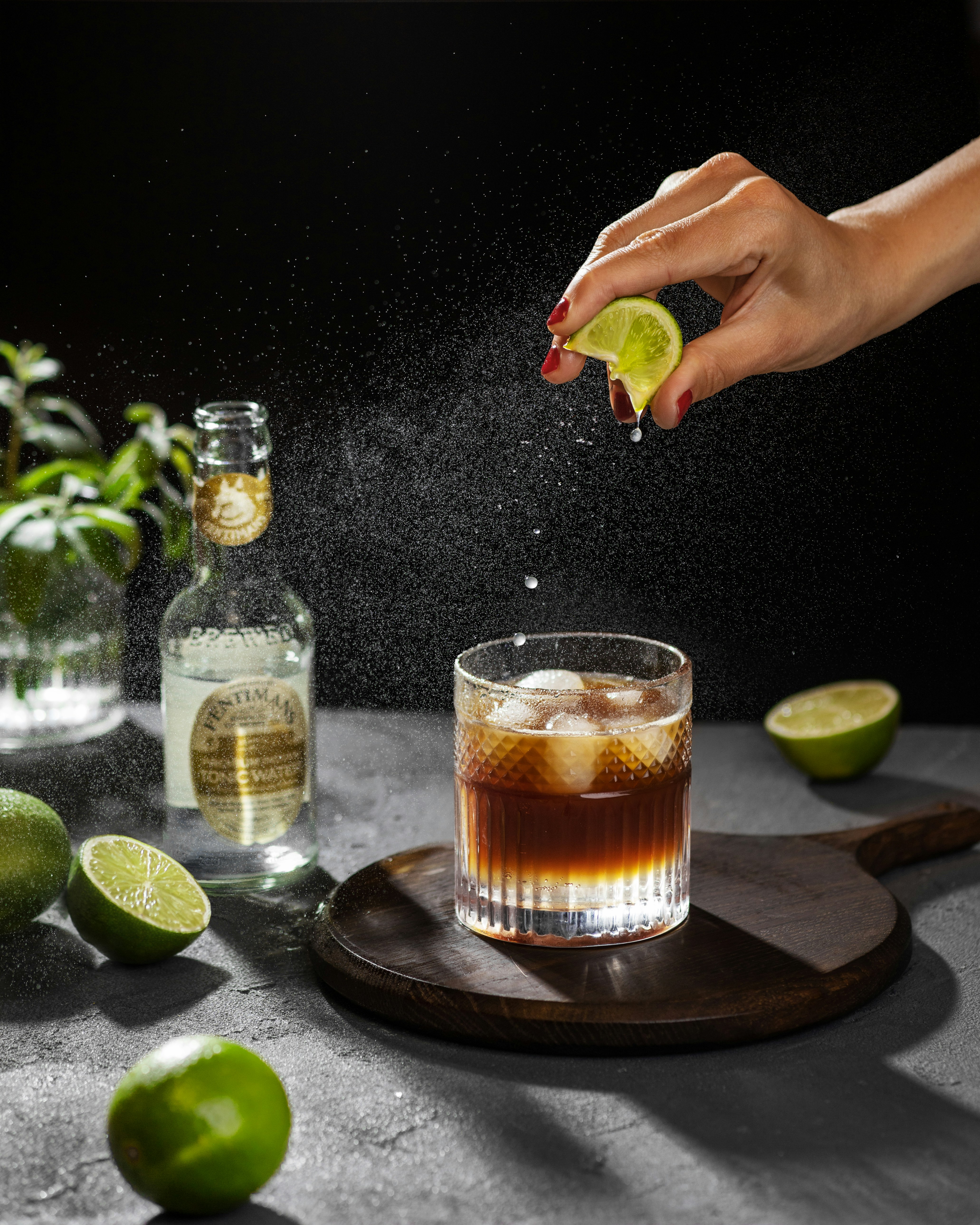 a person sprinkling a lime into a cocktail