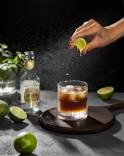 a person sprinkling a lime into a cocktail