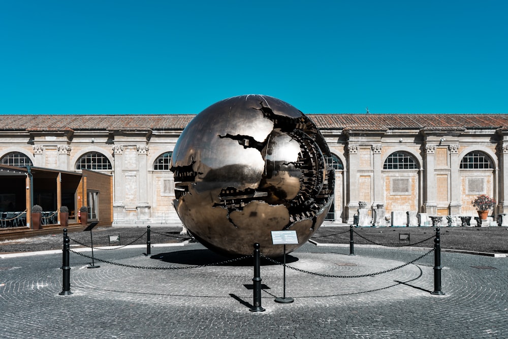 a large metal ball sitting in the middle of a courtyard
