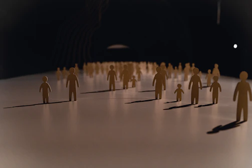 A group of small paper cutout figures on a white surface with long shadows
