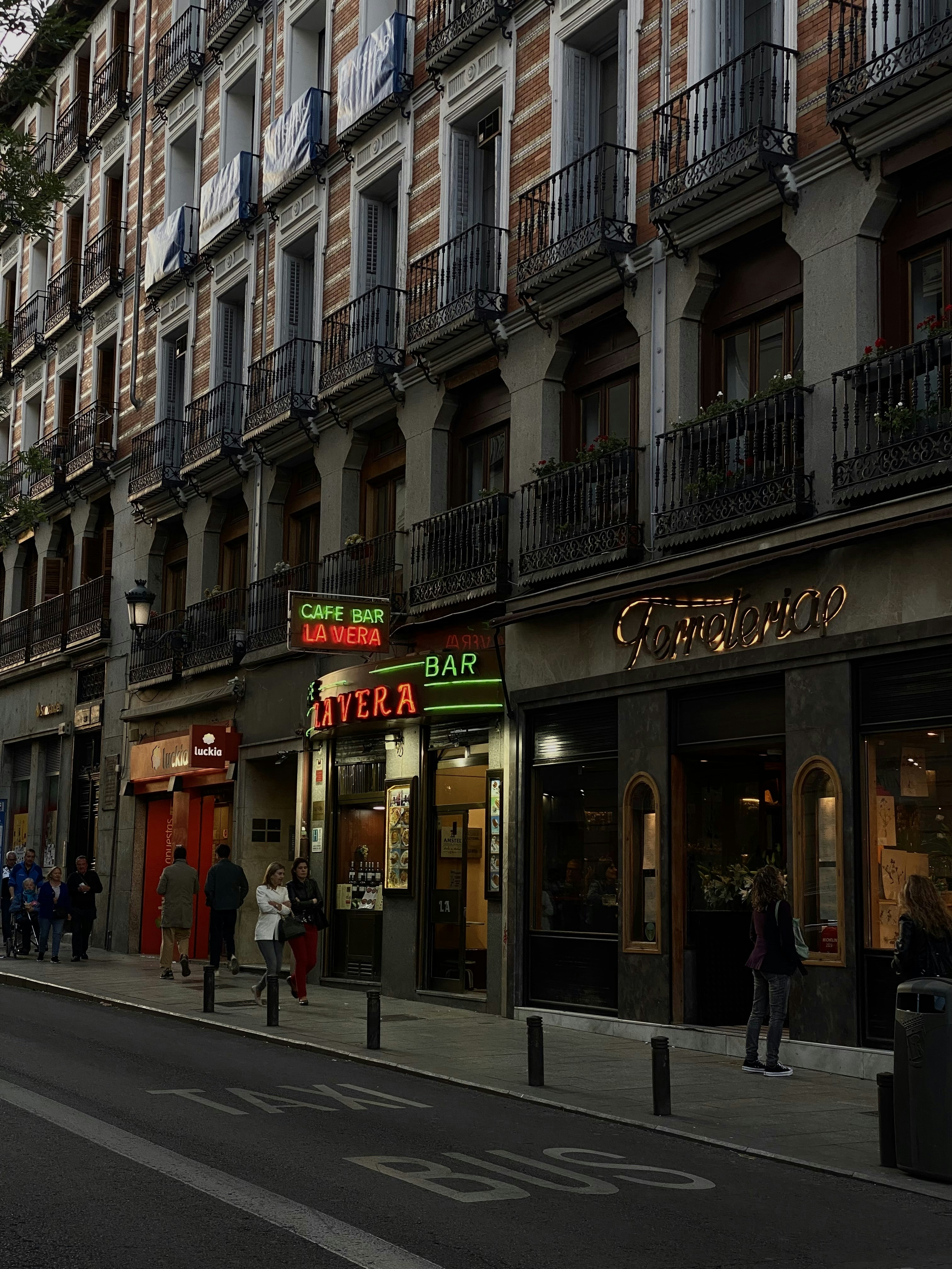 a group of people walking down a street next to tall buildings
