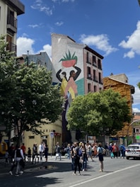 A vibrant street mural featuring cannabis leaves intertwined with Czech cultural symbols under a clear blue sky.