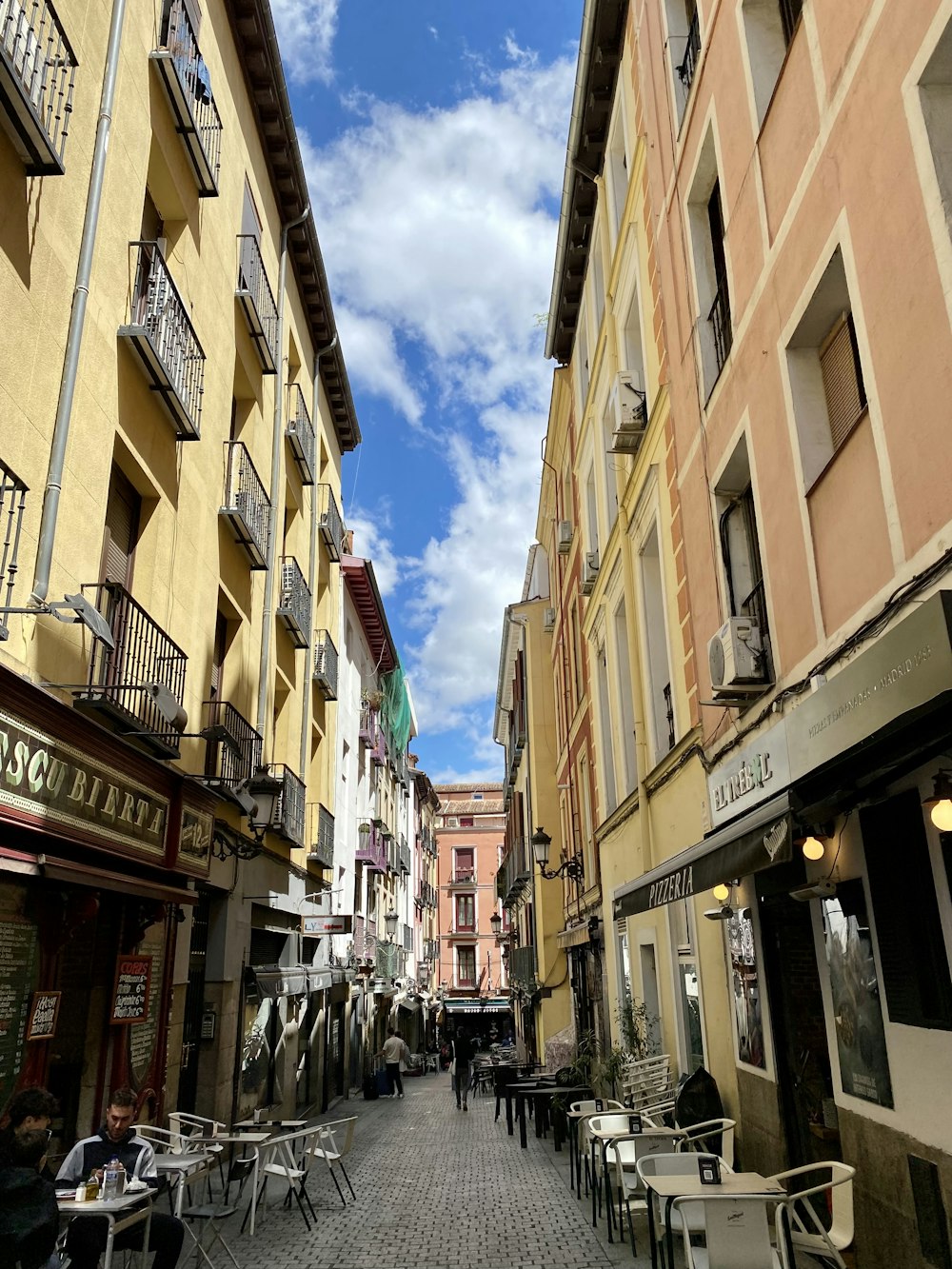 uma rua de paralelepípedos forrada de mesas e cadeiras