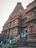 A majestic ancient temple with intricate carvings and detailed stone architecture. The towering structure exudes cultural richness and historical significance. Several people are gathered and walking around the steps at the entrance, suggesting a lively, visited site.