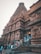 A majestic ancient temple with intricate carvings and detailed stone architecture. The towering structure exudes cultural richness and historical significance. Several people are gathered and walking around the steps at the entrance, suggesting a lively, visited site.