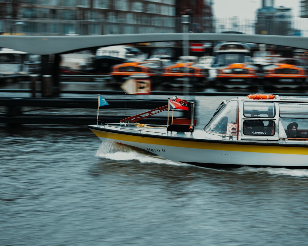 a yellow and white boat traveling down a river