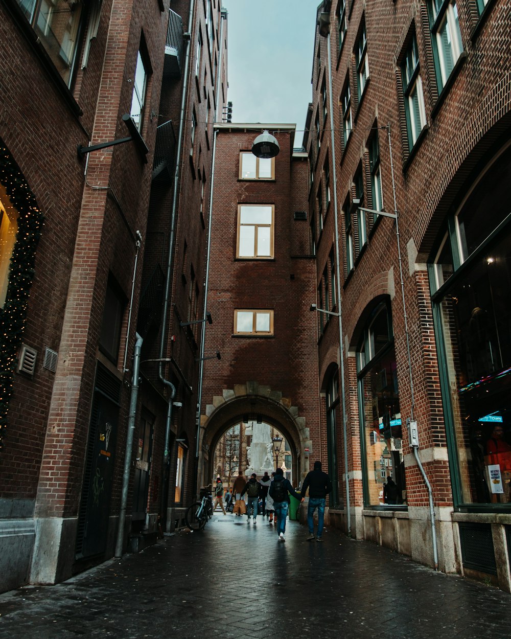 a group of people walking down a street next to tall buildings