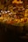 A vibrant spice market with a variety of colorful spices piled in mounds. The warm, golden lighting gives a cozy atmosphere. Various signs in a different language are visible, and a few people are engaged in conversation or transactions.