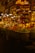 A vibrant spice market with a variety of colorful spices piled in mounds. The warm, golden lighting gives a cozy atmosphere. Various signs in a different language are visible, and a few people are engaged in conversation or transactions.
