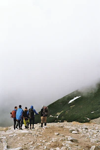 A group of friends trekking together on a misty mountain trail with breathtaking views.