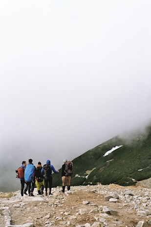 A group walking together on a misty morning, wrapped in cozy scarves and backpacks.