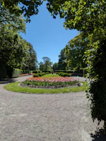 A neatly mowed lawn bordered by vibrant flower beds under a clear sky.