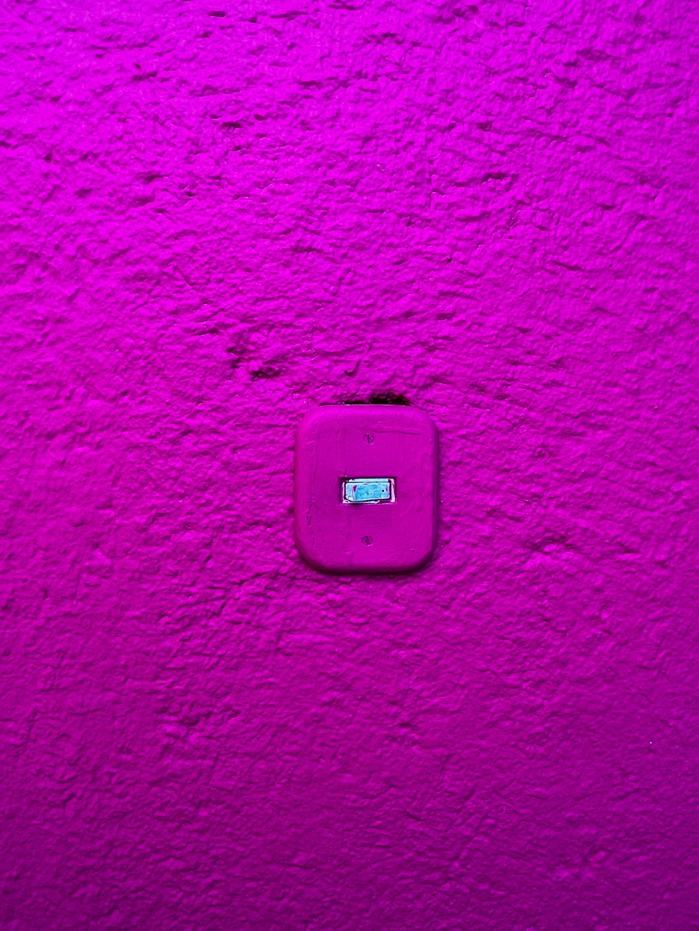 a pink wall with a square button on it