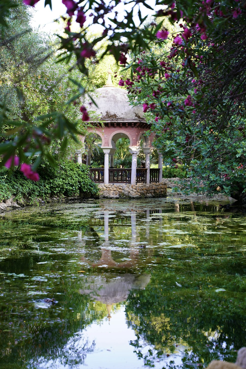 a gazebo in the middle of a pond surrounded by trees