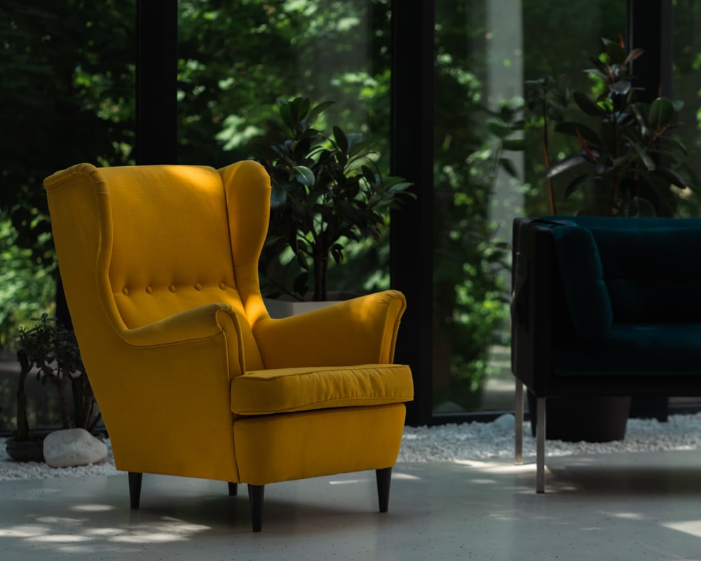 a yellow chair sitting in a living room next to a blue couch