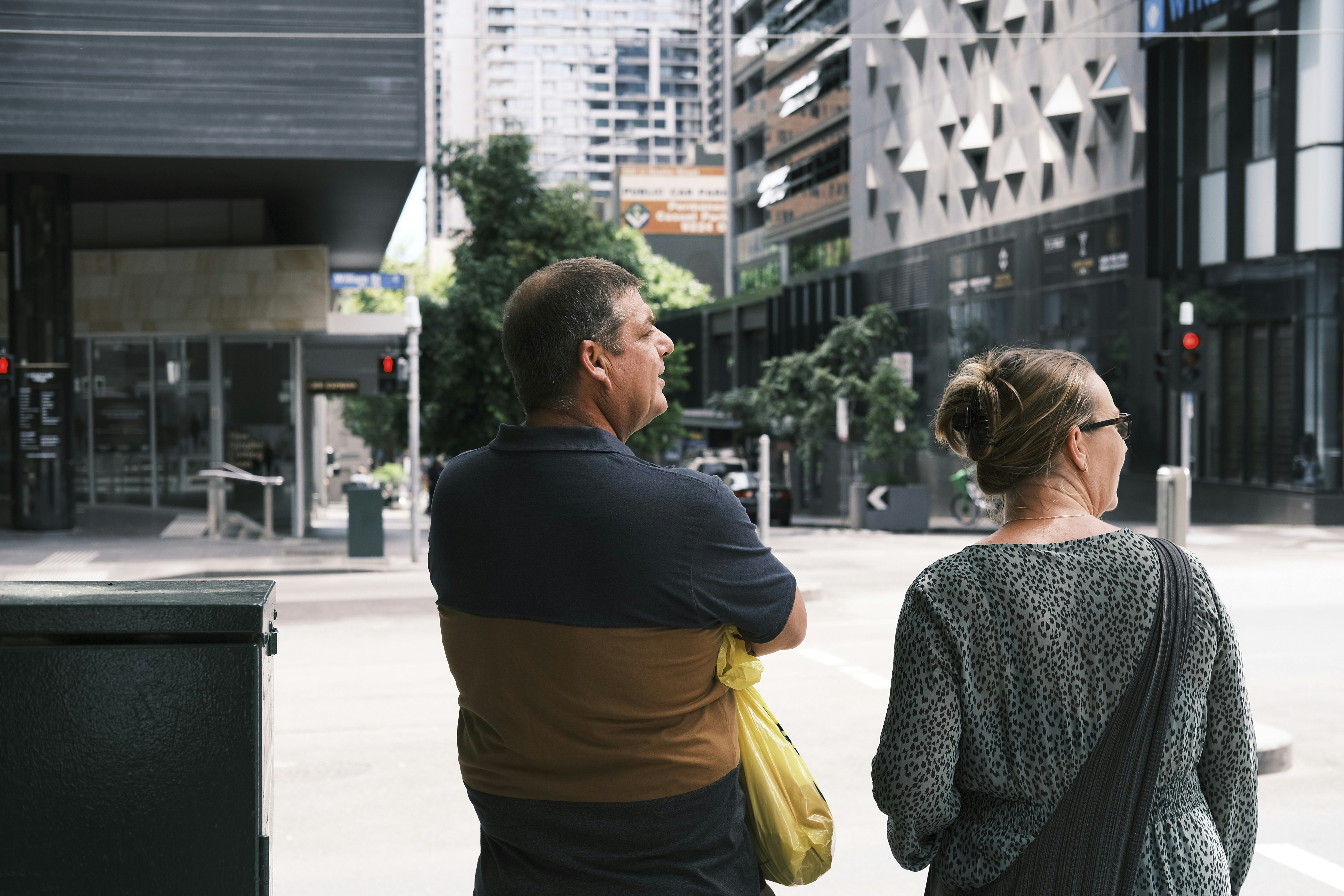 a man and a woman standing next to a trash can