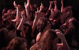 Crowd raising their hands, bathed in charcoal and red lighting, lost in the music.