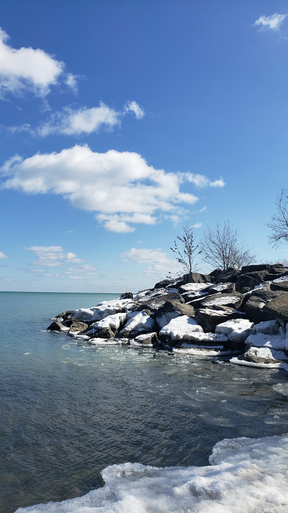 a body of water surrounded by snow covered rocks